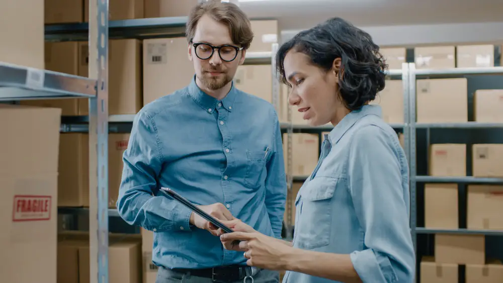 Inventory Manager Shows Digital Tablet Information to a Worker Holding Cardboard Box